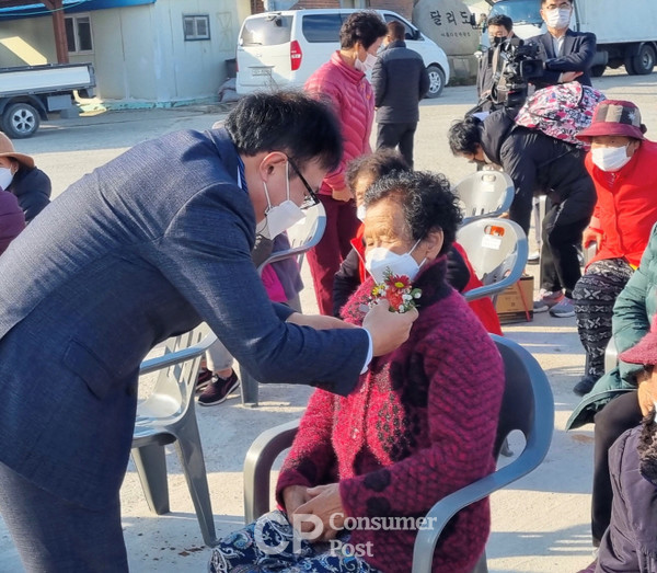 조옥현 전남도의원이 목포시 달동 달리도에서 열린 마을버스 개통식에 참석해 어르신에게 자신에게 있는 꽃을 달아 주고 있다/사진==전남도의회